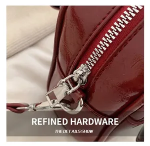 Close-up of silver metal zipper and D-ring on dark red glossy leather shoulder bag