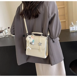 Detailed side view of a cream PU crossbody bag with a star buckle and plush charm