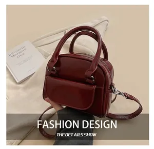 Detail of burgundy glossy patent leather handbag with silver hardware and top handles
