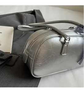 Detail view of silver barrel bag showing metallic crinkled leather and plaid ribbon detail