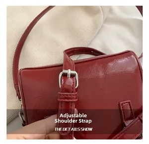 Detail of red patent leather handbag with adjustable silver buckle strap and glossy texture