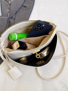 White leather crossbody bag with spacious interior showing phone and cosmetics