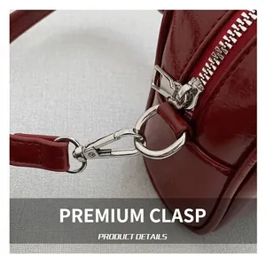Macro detail of dark red patent leather bag featuring silver metal hooks and zippers