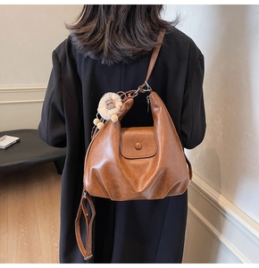 Rear view of a brown faux leather hobo bag with a cute lion plush charm on the strap