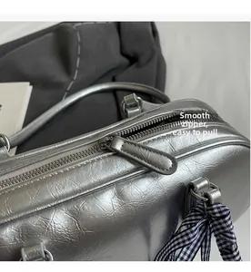 Close-up of silver metallic leather handbag featuring a smooth metal zipper and plaid silk scarf