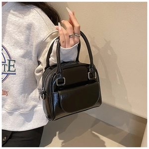 Detail of glossy black patent leather mini handbag with silver zip and metal buckle