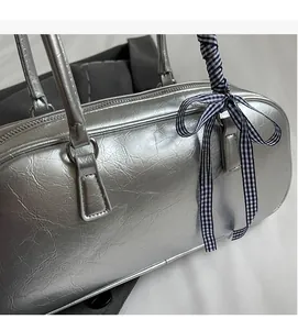 Close-up of metallic silver pillow bag featuring pleated texture and checkered ribbon bow