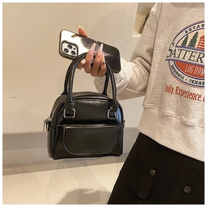 Detail of black glossy patent leather handbag with silver metal buckle and top zipper