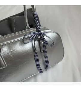 Close-up of silver bowling handbag with textured leather and a checkered ribbon bow