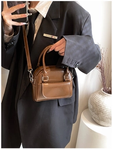 Detail view of the brown glossy patent leather handbag with vintage hardware and strap