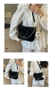 Detail van zwarte crossbody tas met gouden ketting, pluche hanger en riemen