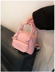 Detailed view of pink patent leather handbag featuring silver metal hardware and double handles