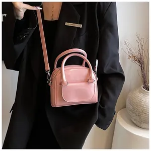 Detail of pink glossy patent leather handbag featuring circular handles and slim strap