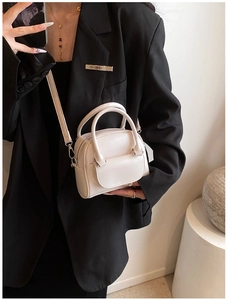 Detail of cream leather mini handbag with dual handles and metal zipper on model