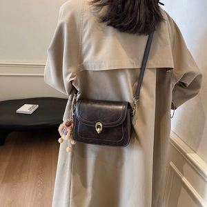 Vintage dark brown crossbody bag with gold buckle on a model in a khaki trench coat