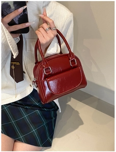 Detail of red patent leather Boston bag with glossy finish and double zippers