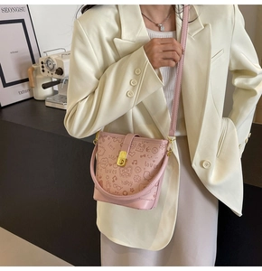 Close-up of a pink bucket bag featuring cute graffiti prints and a gold buckle strap