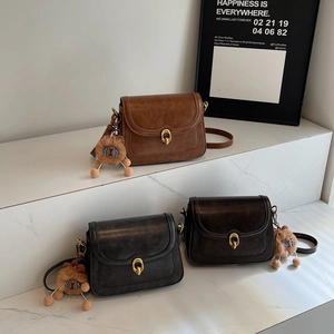 Retro flap crossbody bags in three colors with plush lion charms on marble surface