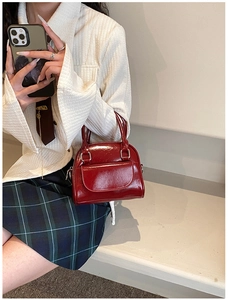 Detail of a burgundy glossy patent leather handbag featuring a vintage box shape design