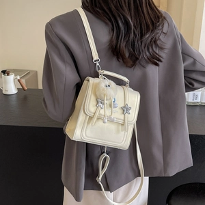 Beige PU leather two-way bag with star decor and plush charm shown on a model