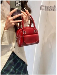 Detail of red patent leather mini doctor bag with silver buckles and a front pocket