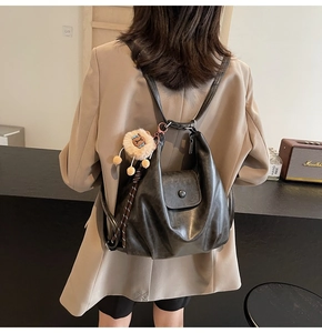 Detail of dark grey soft leather backpack with natural texture and cute lion plush charm