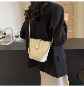 Detail view of cream bucket bag with cartoon embossing and gold metal clasp