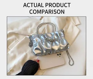 Size comparison of silver pleated handbag with rhinestone bow on white suit background