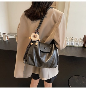 Detailed side view of a large vintage grey hobo bag with a lion plush toy charm on model