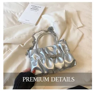 Close-up of pleated silver handbag featuring a sparkling rhinestone bow and chain strap