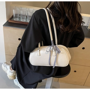 Detailed view of white cylinder bowling bag with pleated PU leather and checkered bow detail