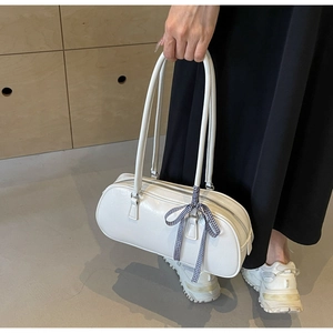 Detail of white leather bow handbag featuring a blue checkered ribbon on the handle