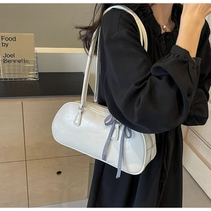 Close-up of white pillow bag with checkered ribbon bow and cracked leather texture