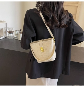 Detail of cream bucket bag featuring embossed heart patterns and gold metal clasp