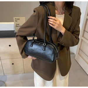 Detail of black bow-style shoulder bag with pleated faux leather texture on model