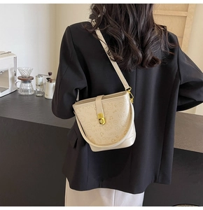 Detail view of cream bucket bag with embossed doodle patterns shown on a model