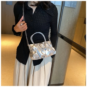 Detail of silver pleated bucket bag with rhinestone bow and crystal handle on model
