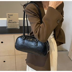 Detail view of black ballet-style pleated Boston bag with long shoulder straps and silver zip