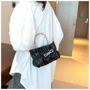 Detail view of black pleated bag featuring sparkling rhinestone bow and crystal handle