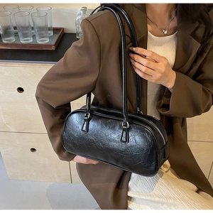 Detail of black wrinkled faux leather bowling bag with glossy finish and long handles