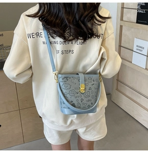 Detail of light blue bucket bag with black graffiti prints and golden turn-lock closure