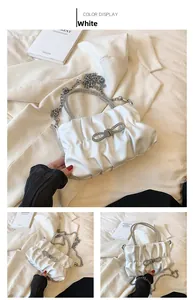 Close-up of white pleated bucket bag with sparkling diamond bow and handle details