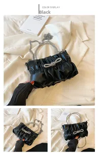 Detail of black pleated handbag with rhinestone bow decoration and crystal handle