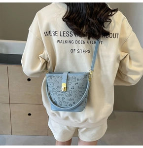 Back view of a light blue bucket bag with black graffiti prints worn by a model