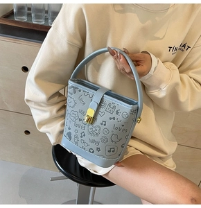 Detail of light blue bucket bag featuring textured leather and sweet hand-drawn graffiti