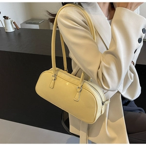 Detail of cream yellow leather baguette bag with subtle wrinkled texture and silver hardware