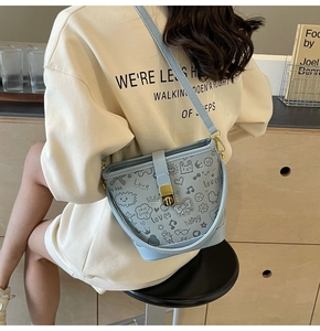 Detail of light blue bucket bag with black graffiti art and golden twist lock closure