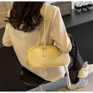 Detail of a bright yellow cylindrical shoulder bag with sleek straps and silver buckles