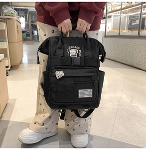 Detail of a black multi-pocket canvas backpack with embroidered patches and durable handles