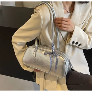 Detailed macro view of silver metallic handbag with pleated texture and plaid ribbon bow